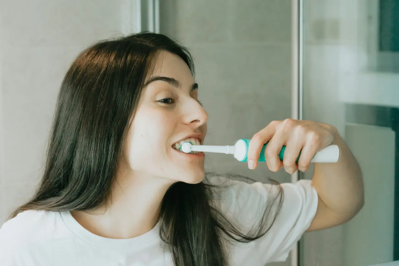 The Root Causes of Bad Breath. Woman Brushing Her Teeth